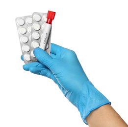 Scientist in protective gloves holding pills and test tube with label Covid-19 on white background, closeup