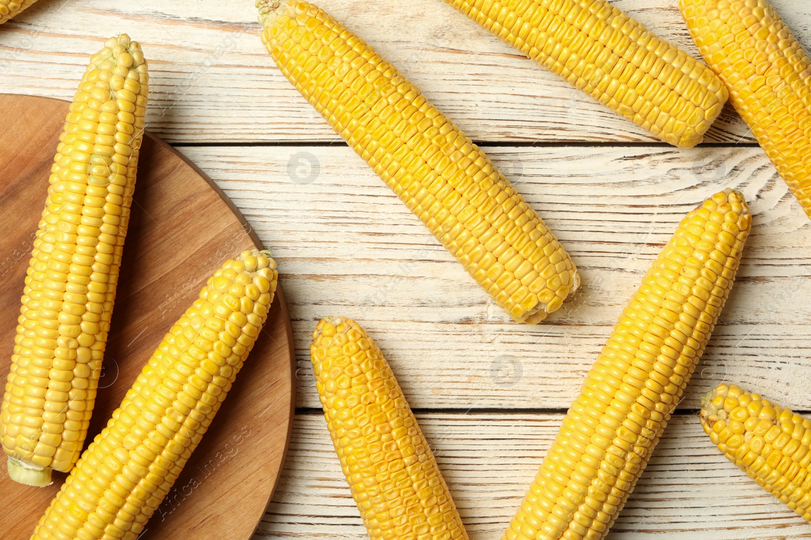 Photo of Corn cobs on white wooden table, flat lay