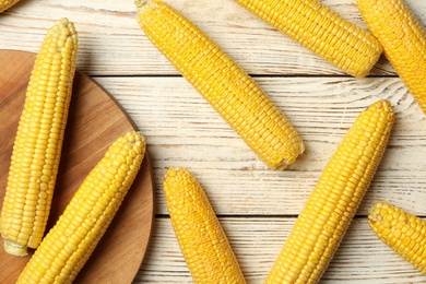 Corn cobs on white wooden table, flat lay