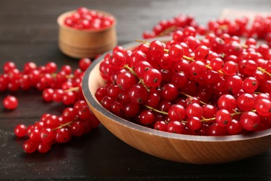 Photo of Delicious red currants in bowl on dark wooden table, closeup