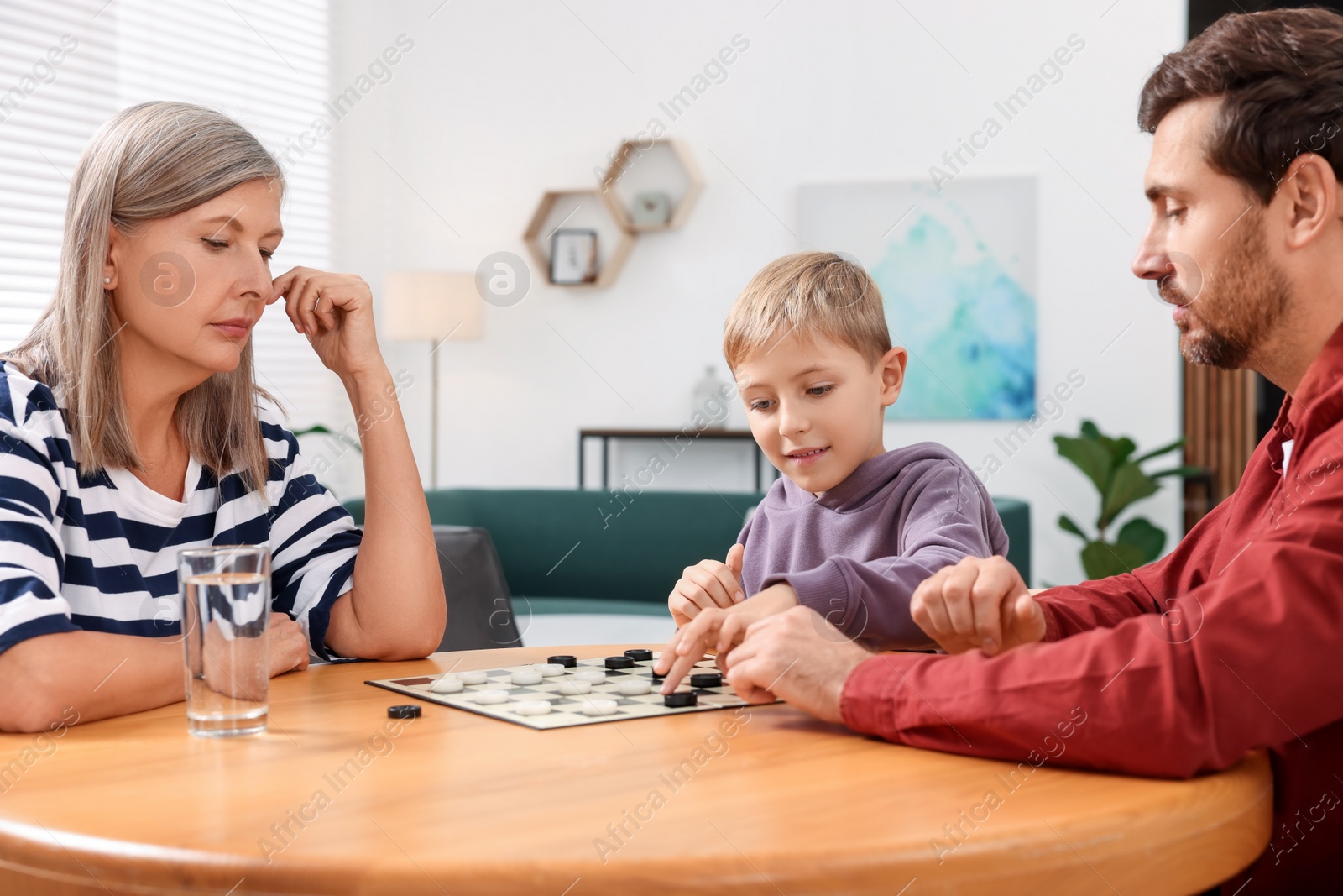 Photo of Family playing checkers at wooden table in room