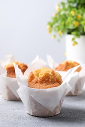 Delicious sweet muffins on light grey textured table, closeup. Space for text