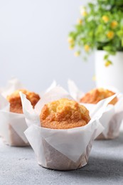 Photo of Delicious sweet muffins on light grey textured table, closeup. Space for text