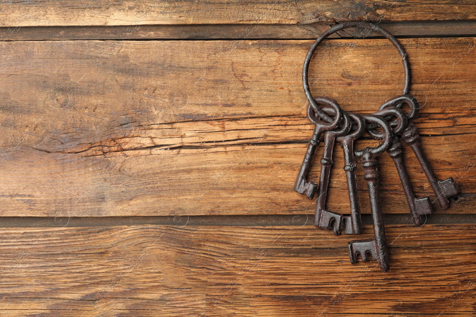 Photo of Bunch of steel keys on wooden background, top view with space for text. Safety concept