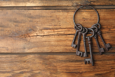 Bunch of steel keys on wooden background, top view with space for text. Safety concept