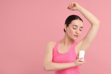 Photo of Beautiful woman applying deodorant on pink background, space for text