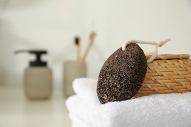 Photo of Pumice stone with wicker basket and soft towel on white table, closeup. Space for text