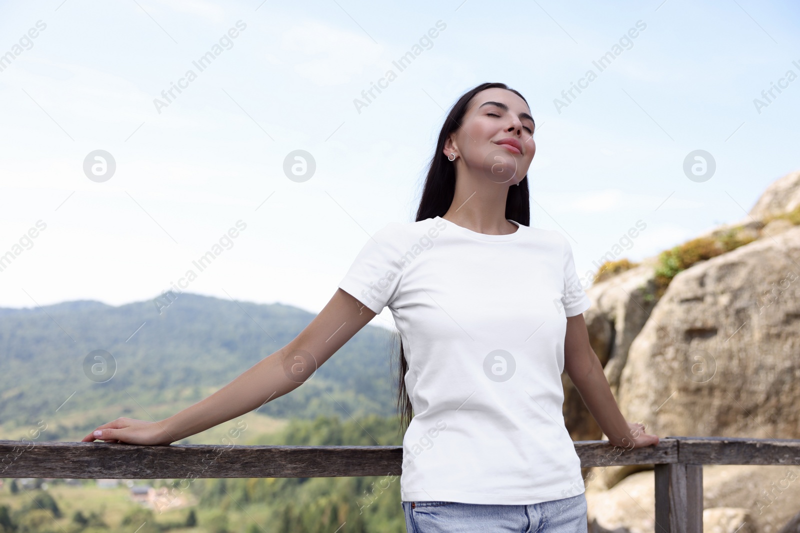 Photo of Feeling freedom. Beautiful woman enjoying nature near wooden railing in mountains