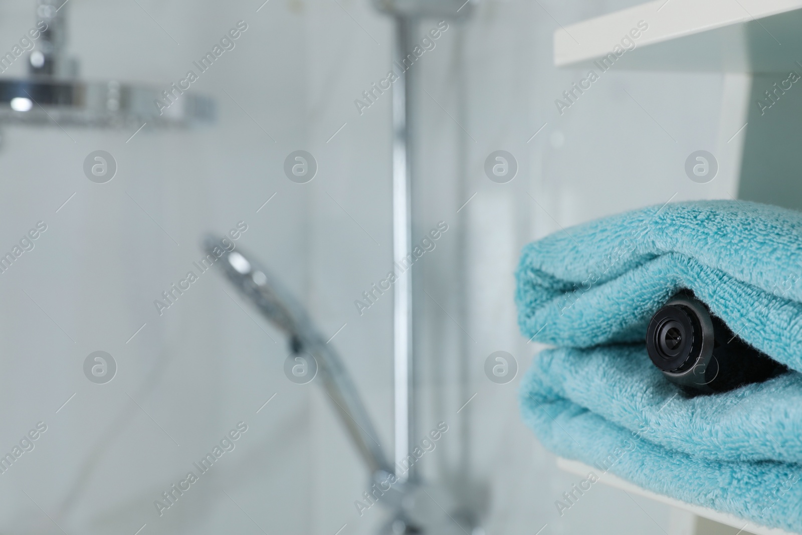 Photo of Camera hidden between towels in bathroom, space for text