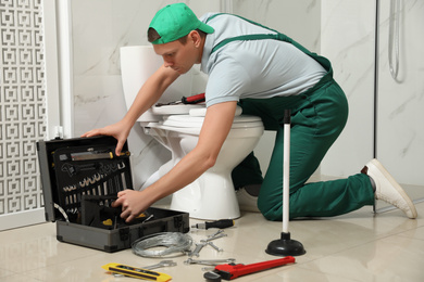Professional plumber repairing toilet tank in bathroom