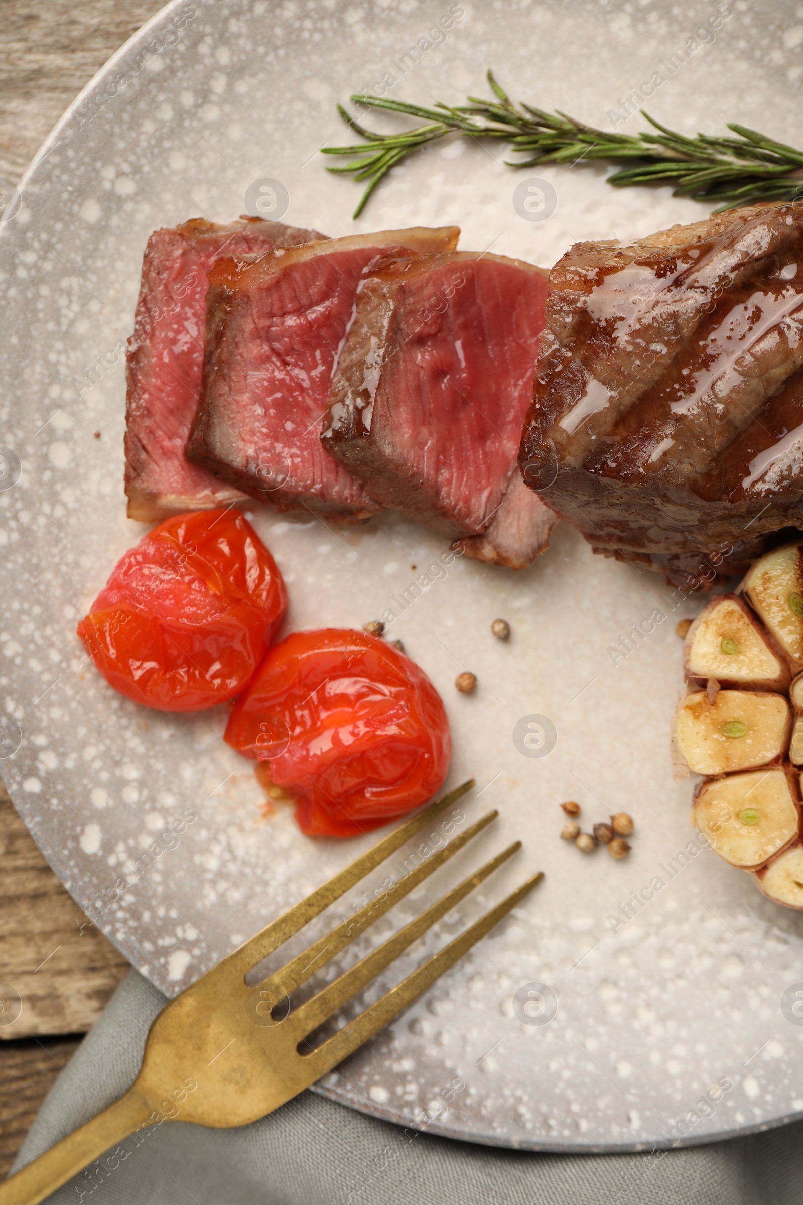 Photo of Delicious grilled beef steak served with spices and tomatoes on table, top view