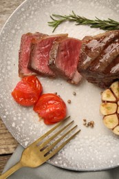 Photo of Delicious grilled beef steak served with spices and tomatoes on table, top view