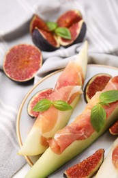 Photo of Tasty melon, jamon and figs served on table, closeup
