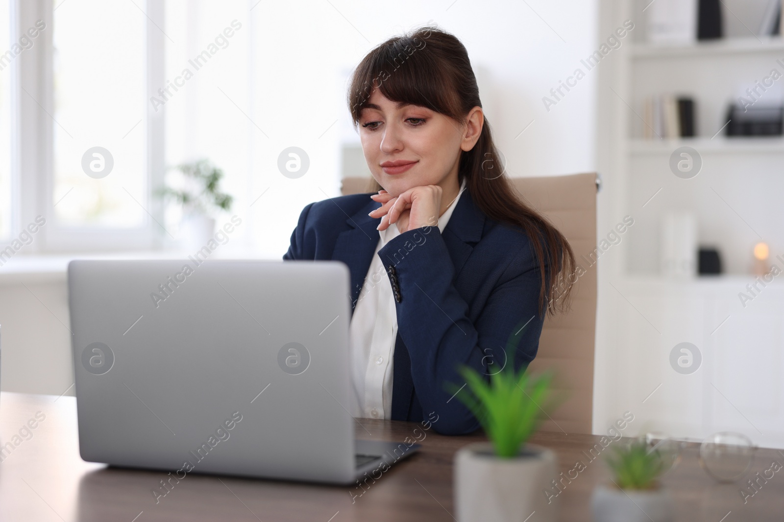 Photo of Woman watching webinar at wooden table in office