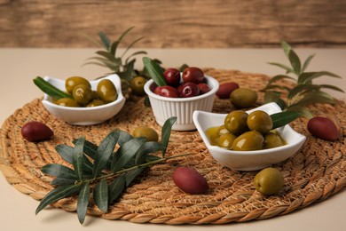 Photo of Olives and tree twigs on beige table