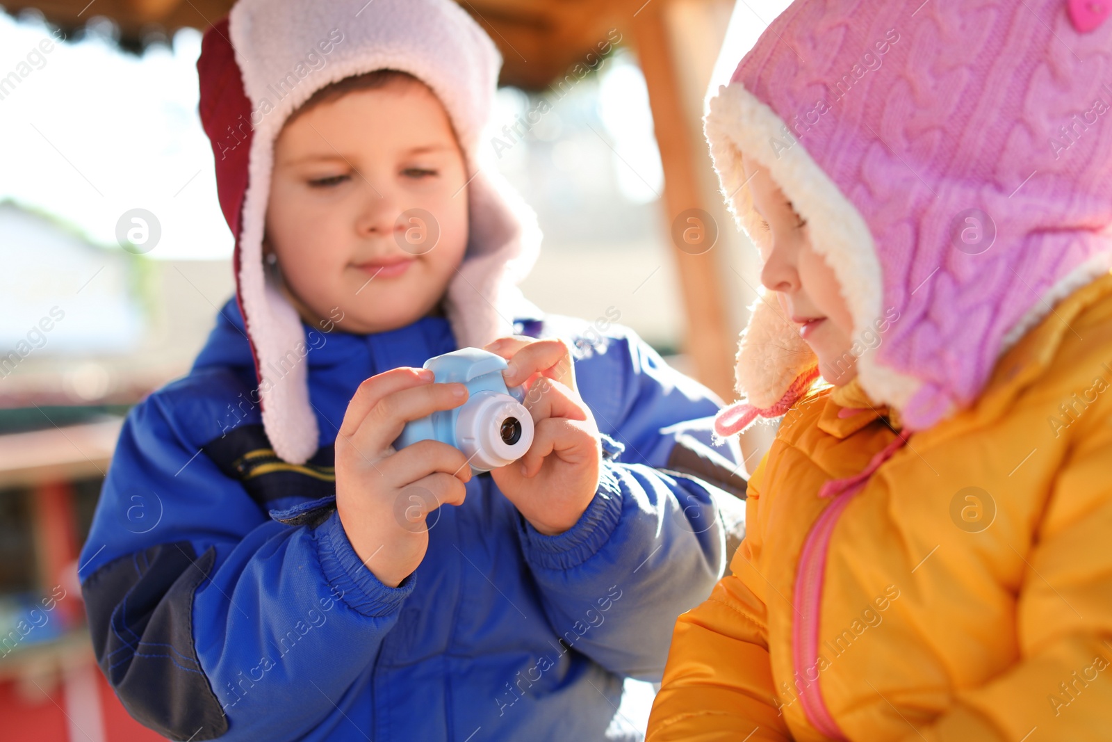 Photo of Little boy taking picture of girl outdoors. Future photographer