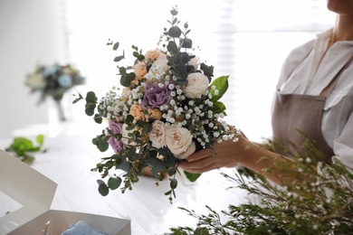 Photo of Florist holding beautiful wedding bouquet indoors, closeup