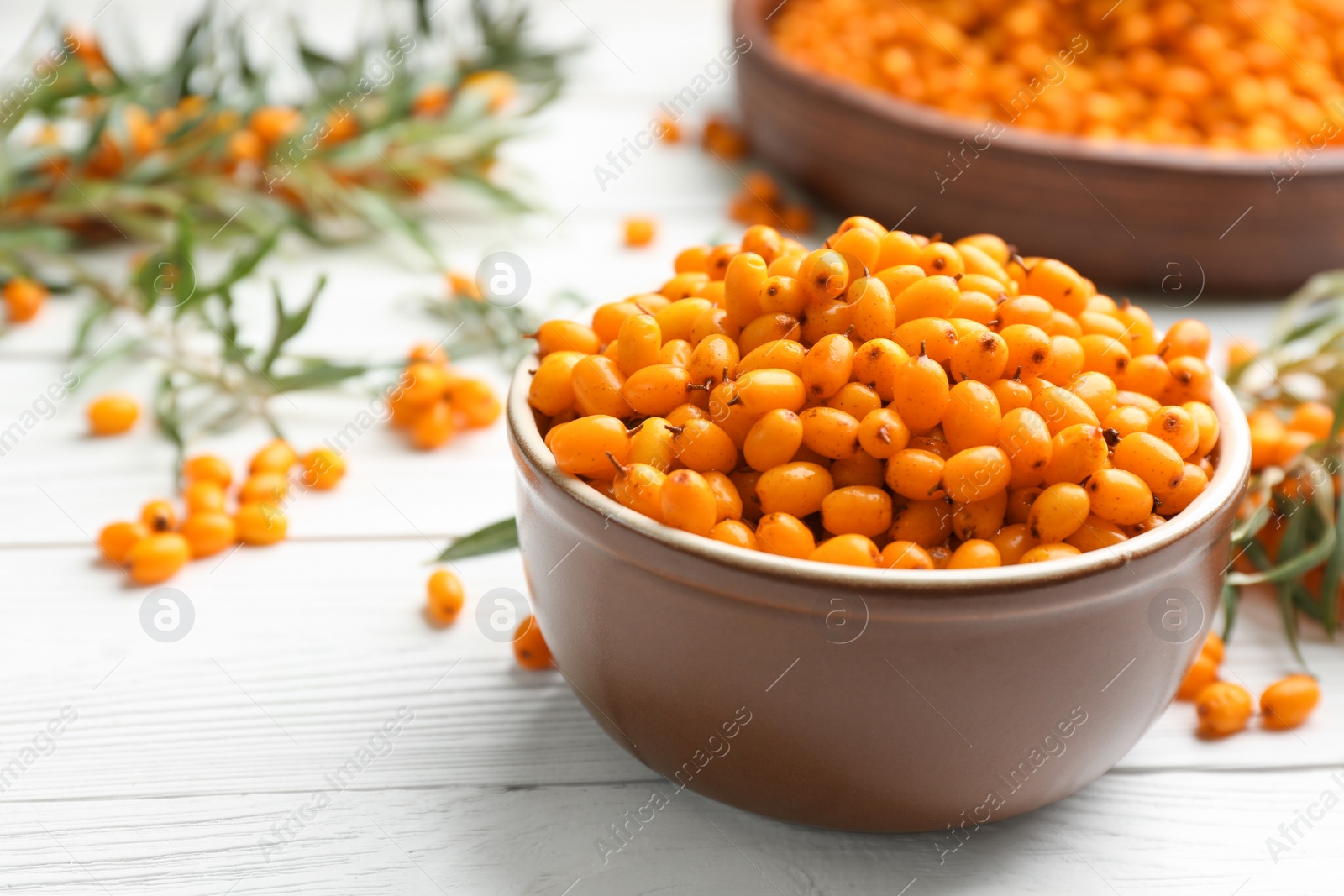 Photo of Fresh ripe sea buckthorn in bowl on white wooden table