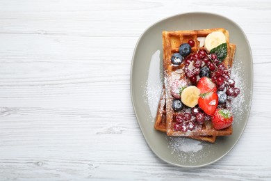 Photo of Plate of delicious Belgian waffles with berries and powdered sugar on white wooden table, top view. Space for text
