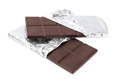 Photo of Delicious dark chocolate bars wrapped in foil isolated on white