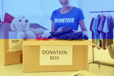 Image of Double exposure of volunteer packing donation boxes and Ukrainian flag, closeup. Help during war