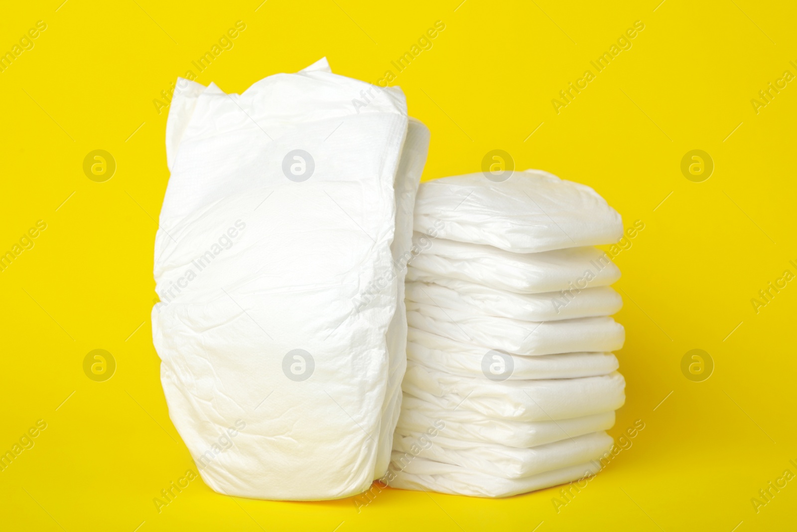 Photo of Stack of baby diapers on yellow background