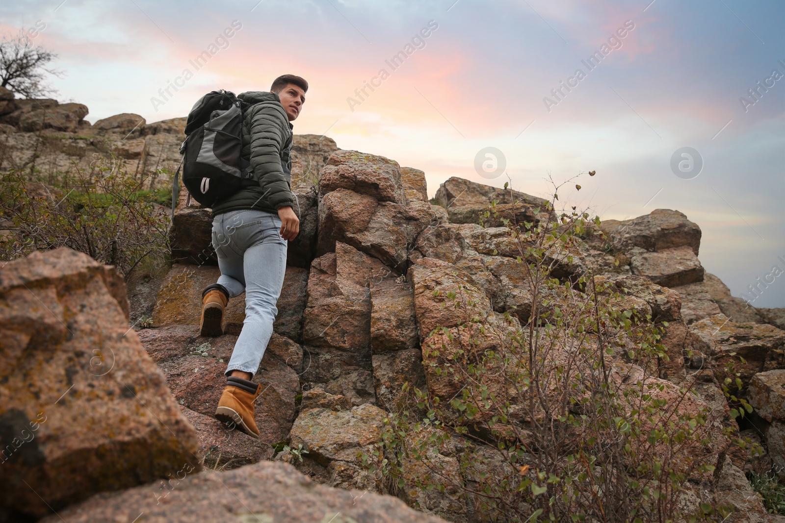 Photo of Hiker with backpack climbing up mountain on autumn day