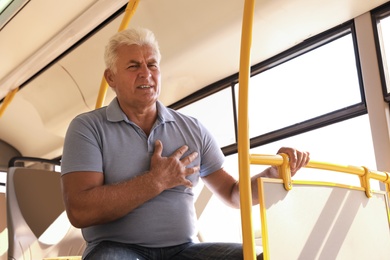 Image of Senior man having heart attack in public transport