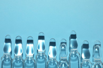 Photo of Pharmaceutical ampoules with medication on light blue background, flat lay. Space for text