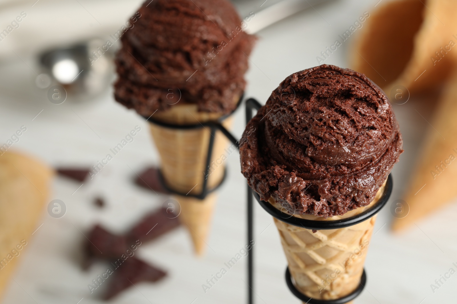 Photo of Chocolate ice cream scoops in wafer cones on stand, closeup