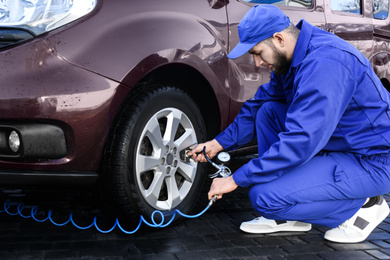 Photo of Mechanic checking tire air pressure at car service