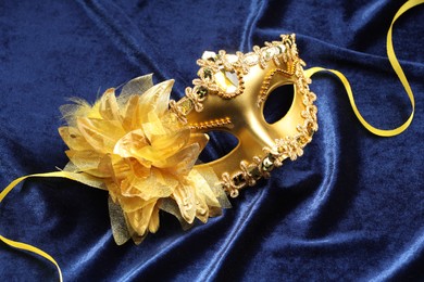 Photo of Theater arts. Golden venetian carnival mask on blue fabric, above view