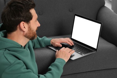 Photo of Handsome man using laptop on grey couch