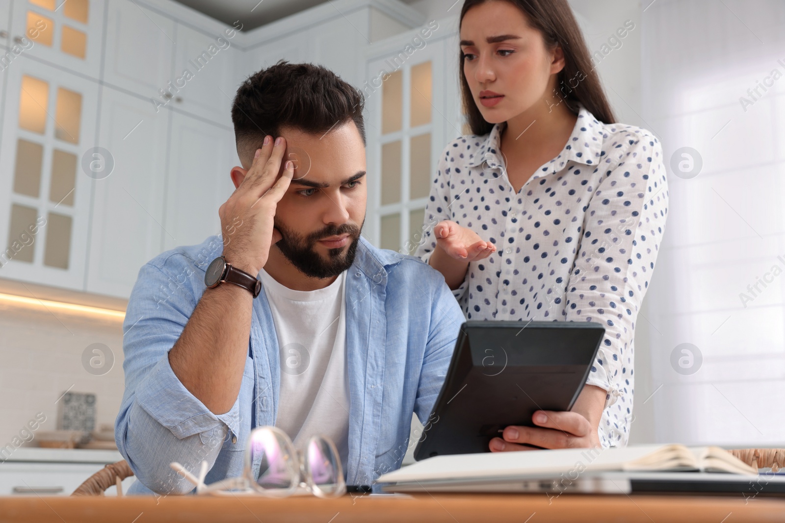 Photo of Young couple discussing family budget in kitchen