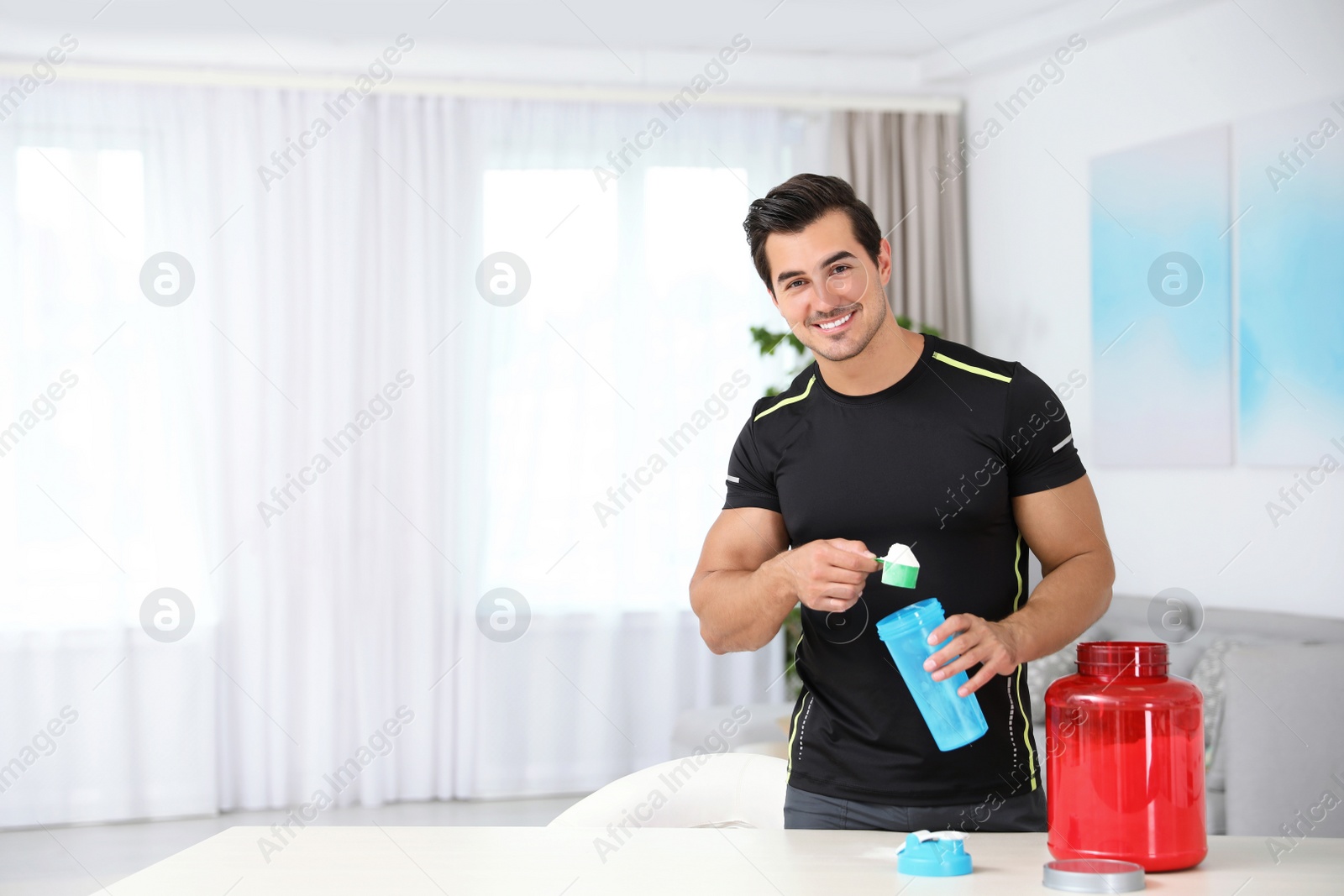 Photo of Young athletic man preparing protein shake at home, space for text