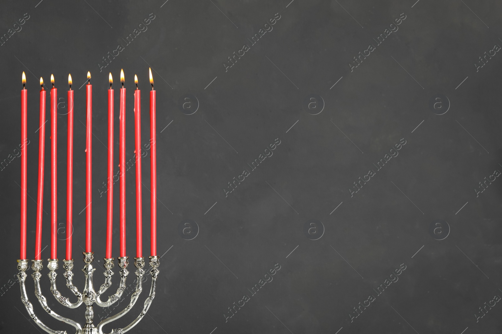 Photo of Silver menorah with burning candles on grey background, space for text. Hanukkah celebration