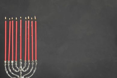 Photo of Silver menorah with burning candles on grey background, space for text. Hanukkah celebration