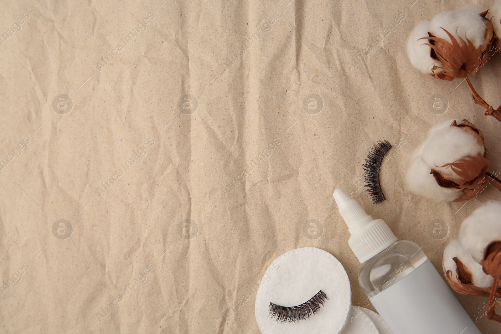 Photo of Flat lay composition with makeup remover and cotton flowers on crumpled paper, space for text