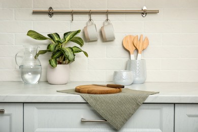 Photo of Clean towel, wooden cutting board and knife on countertop in kitchen