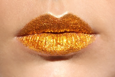 Photo of Beautiful young model with golden lips makeup, closeup