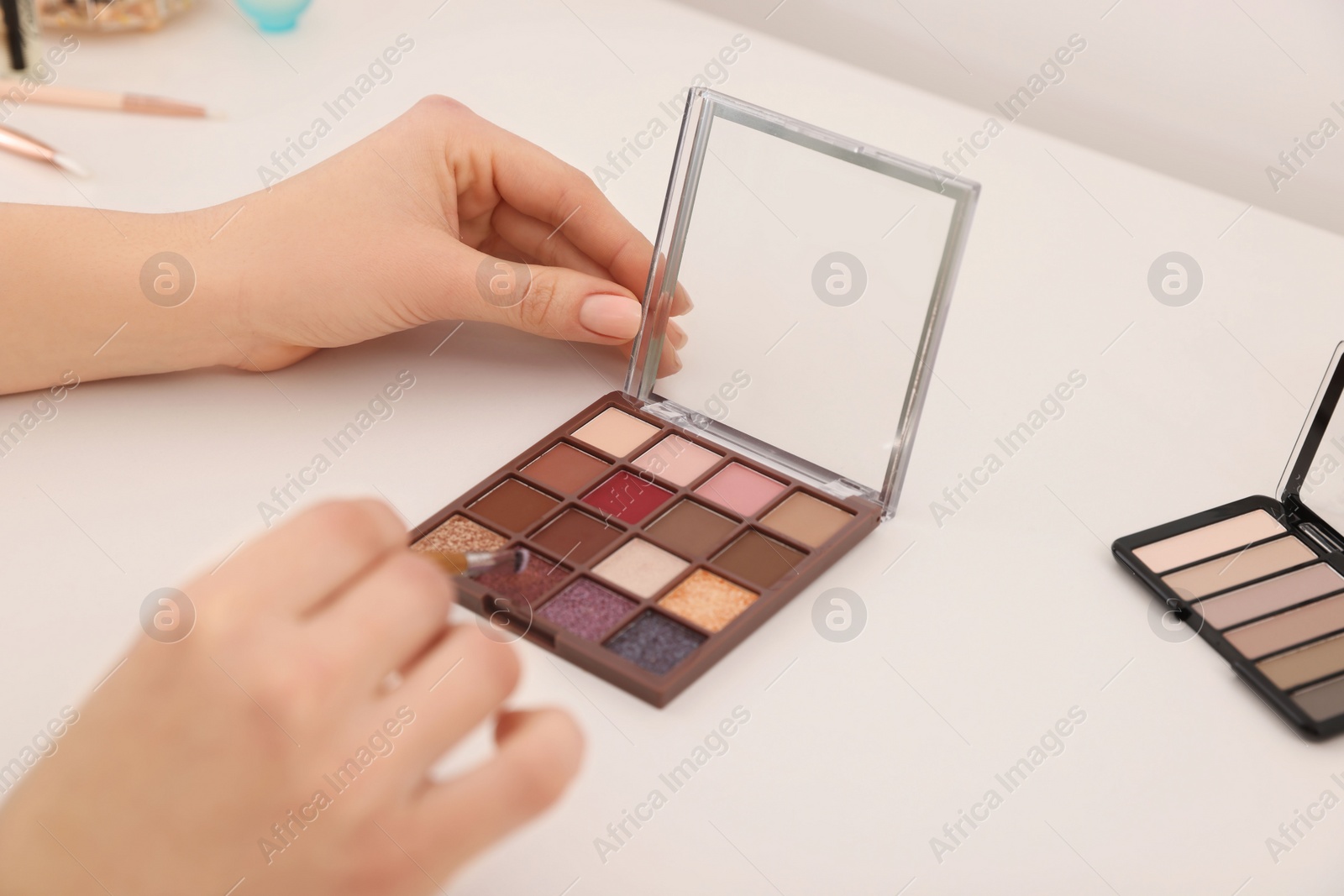 Photo of Woman with eyeshadow palette and brush at dressing table, closeup