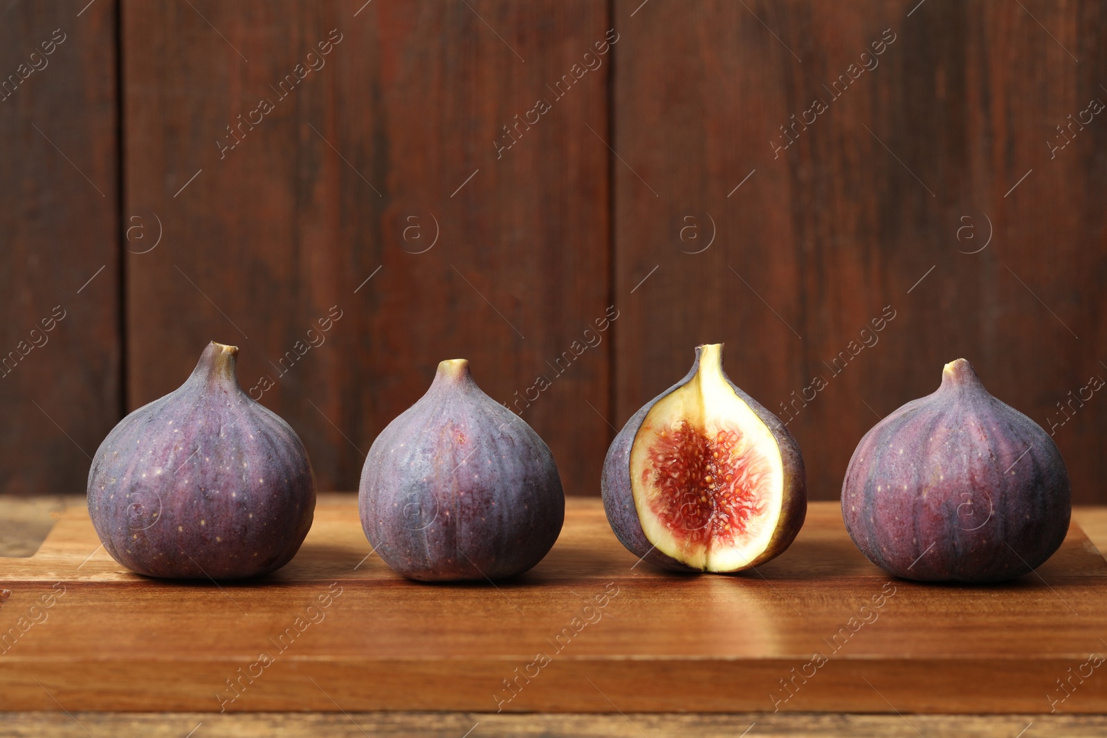 Photo of Whole and cut tasty fresh figs on wooden table