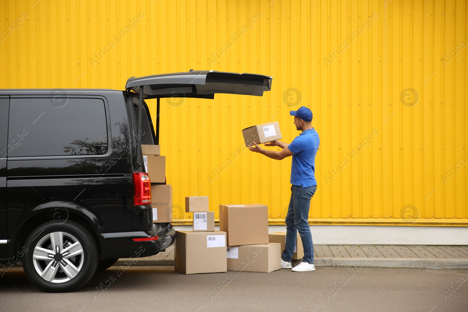 Photo of Courier with parcels near delivery van outdoors