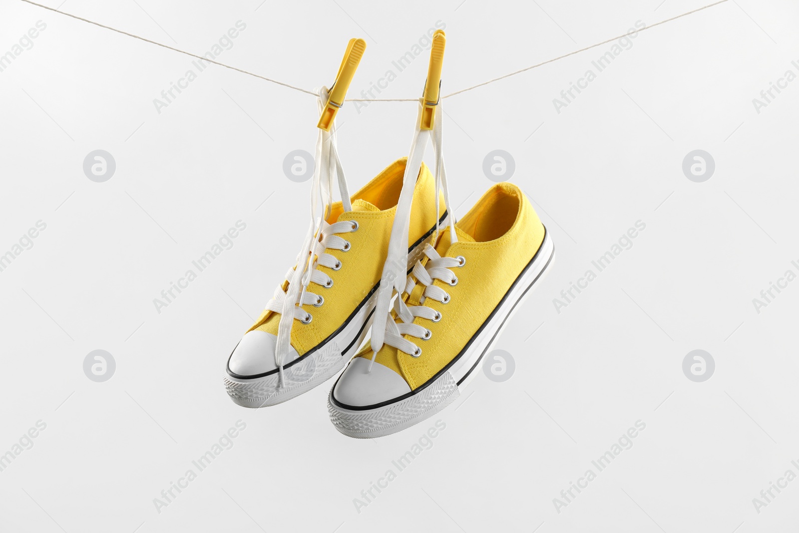 Photo of Stylish sneakers drying on washing line against light grey background