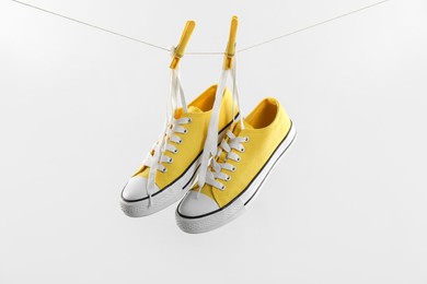 Photo of Stylish sneakers drying on washing line against light grey background