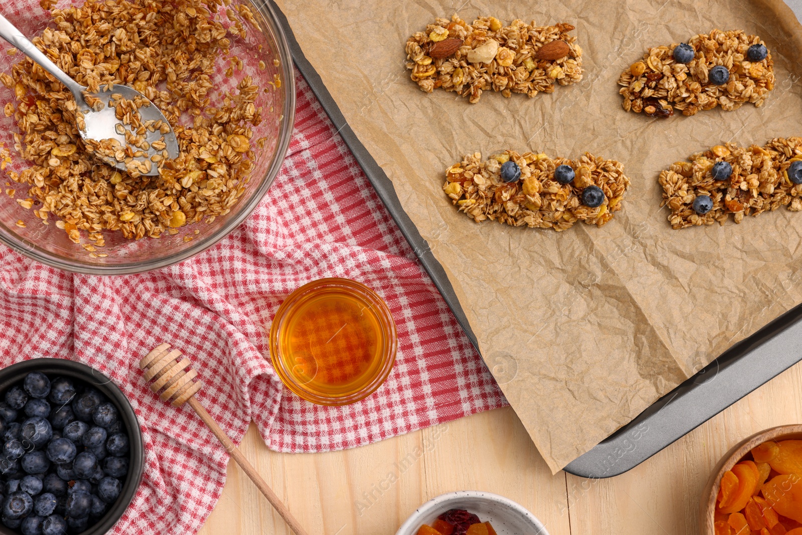 Photo of Making granola bars. Baking tray and ingredients on wooden table, flat lay