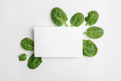 Blank card and fresh spinach leaves isolated on white, top view. Space for text