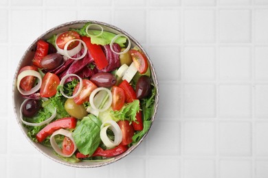 Photo of Bowl of tasty salad with leek and olives on white tiled table, top view. Space for text