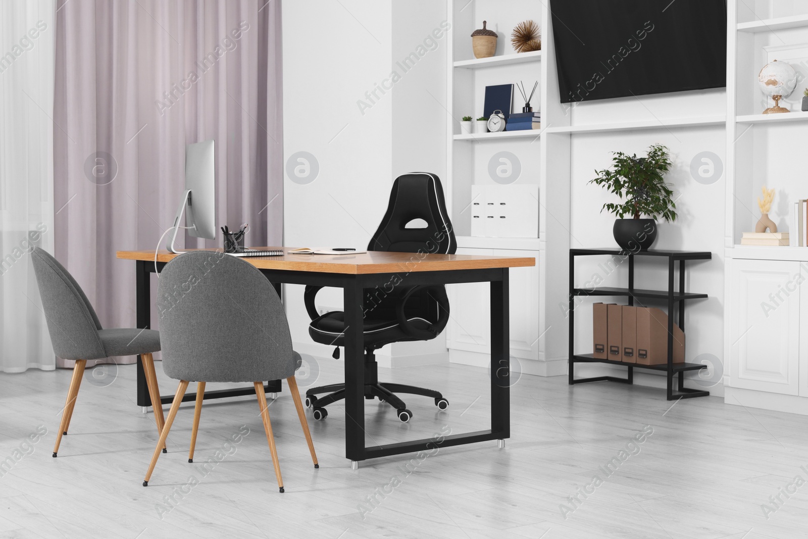 Photo of Stylish director's workplace with wooden table, tv zone, shelves and comfortable armchairs in room. Interior design