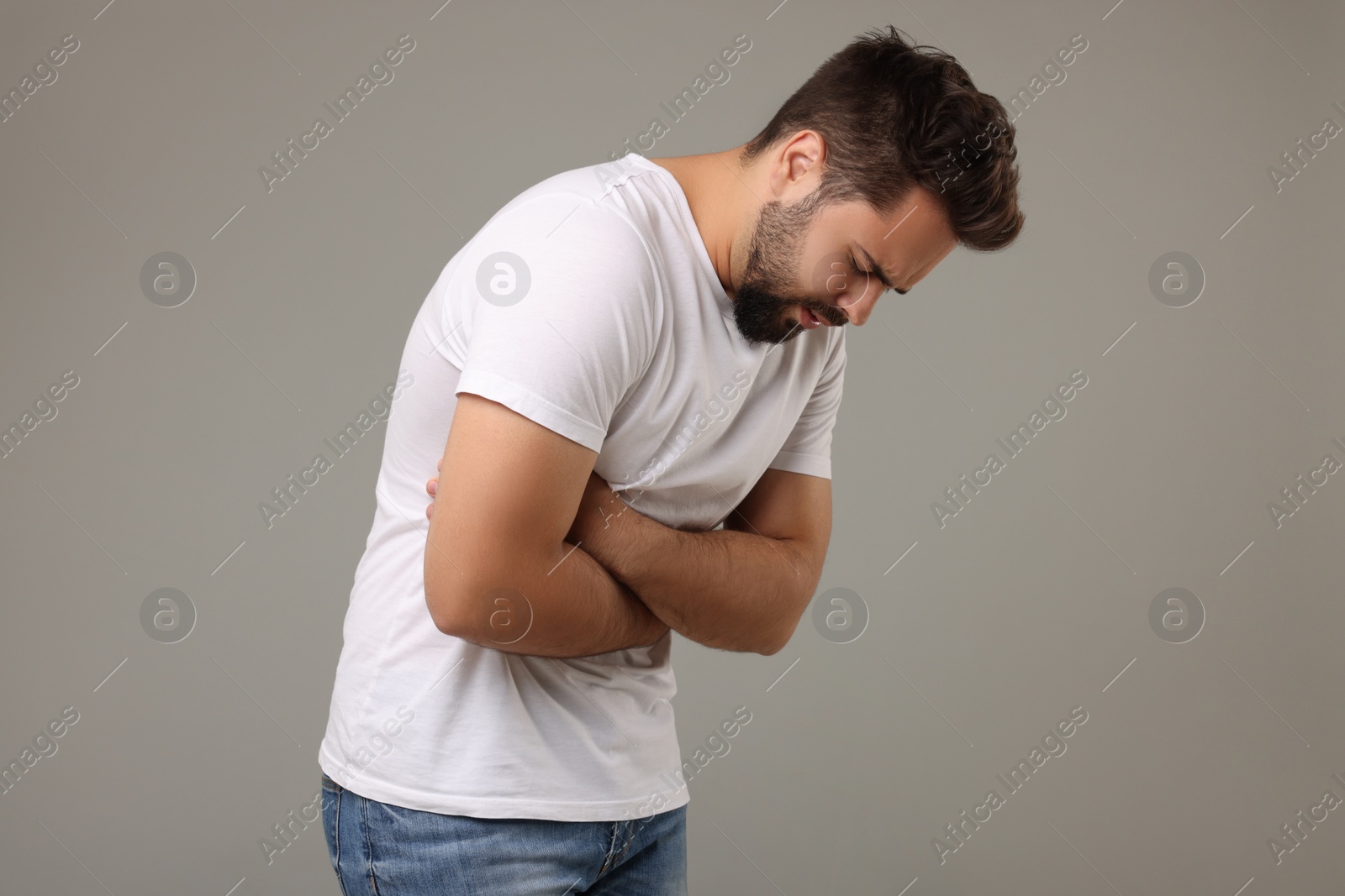 Photo of Young man suffering from stomach pain on light grey background